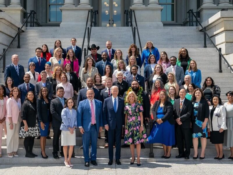 Group of adults standing at the steps to the White House with President Joe Biden and First Lady Jill Biden, formally dressed and smiling