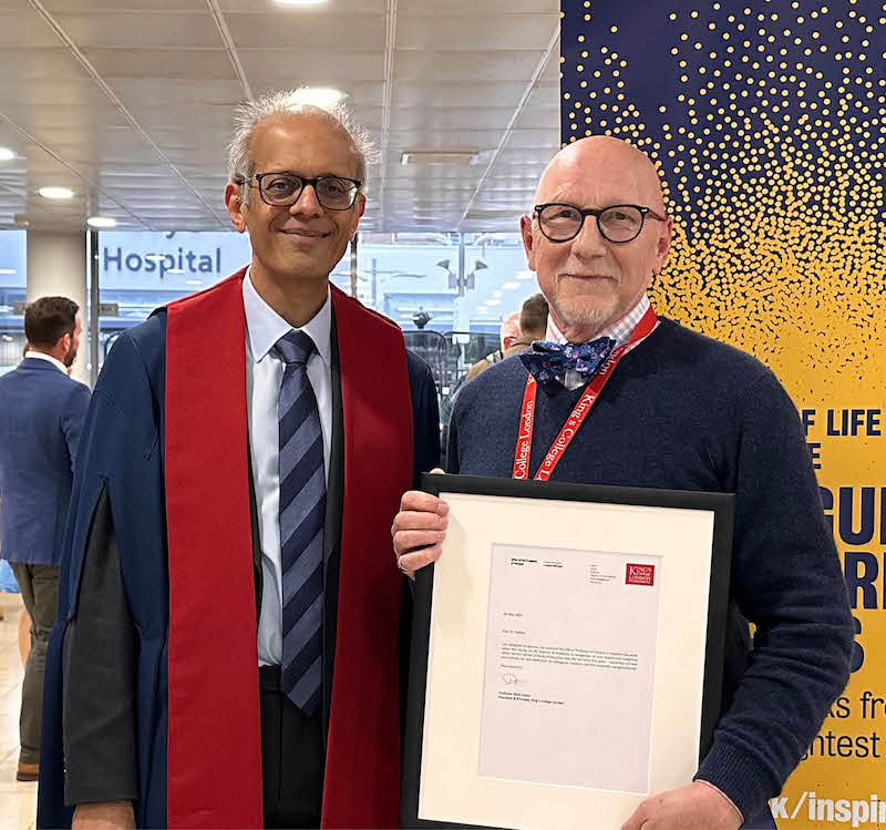 Two men in glasses smiling at King's College London's graduation ceremony, one wearing graduation robes